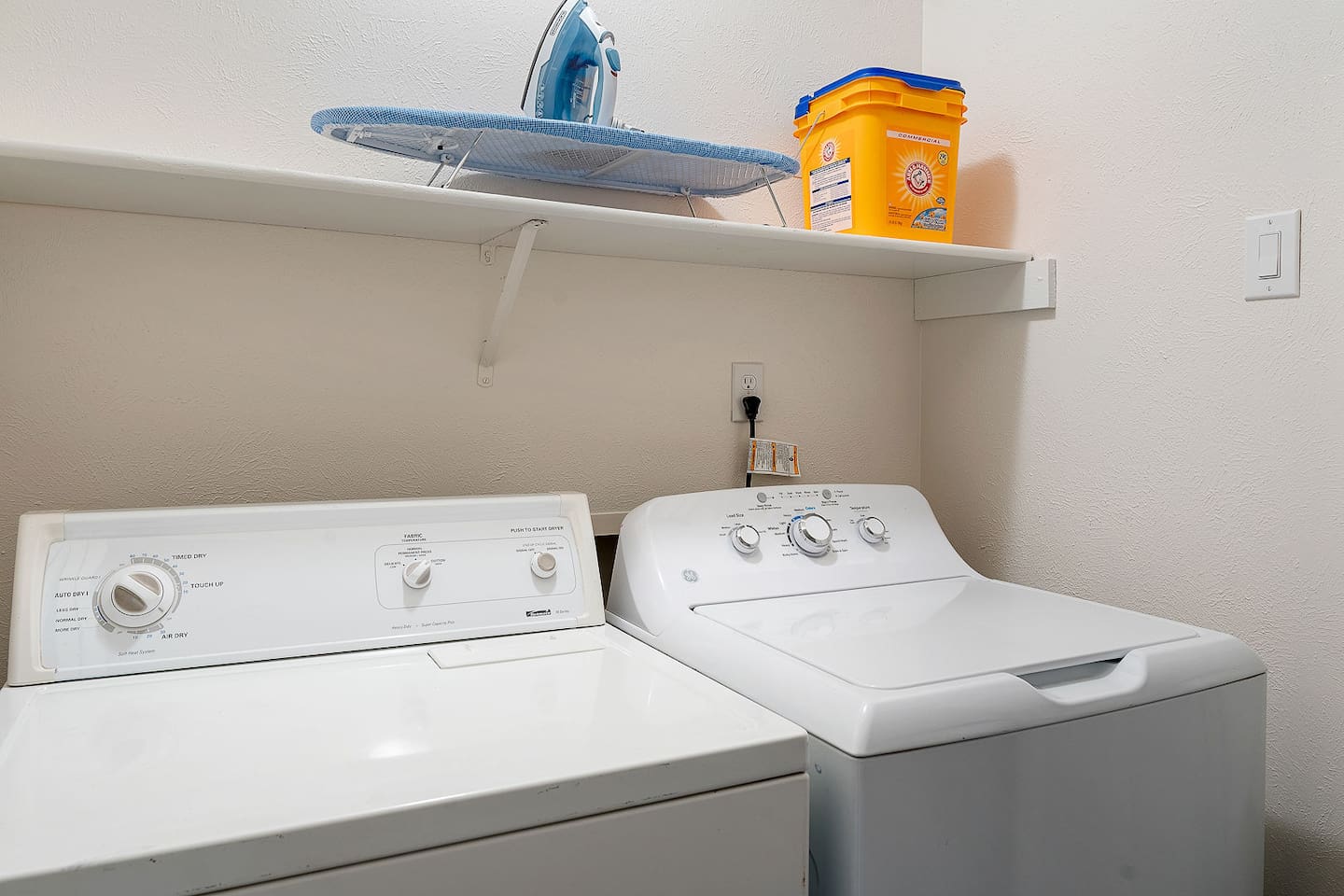 Discover the convenience of an in-unit laundry area with a washer, dryer, iron, ironing board, detergent and ample shelving.
