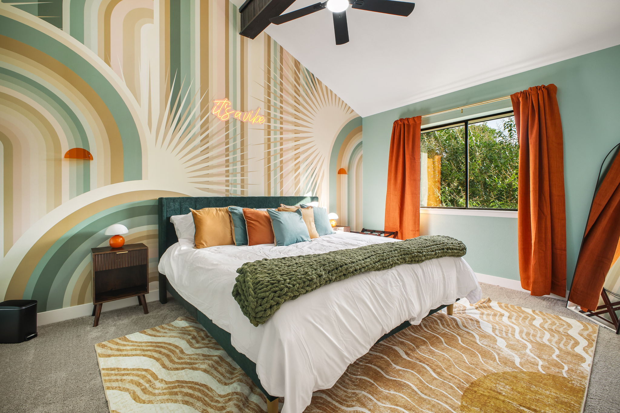 Bedroom 4: Warm desert-inspired colors and sunburst mural create an unforgettable atmosphere, especially with the "It's a vibe" neon sign adding a playful touch.
