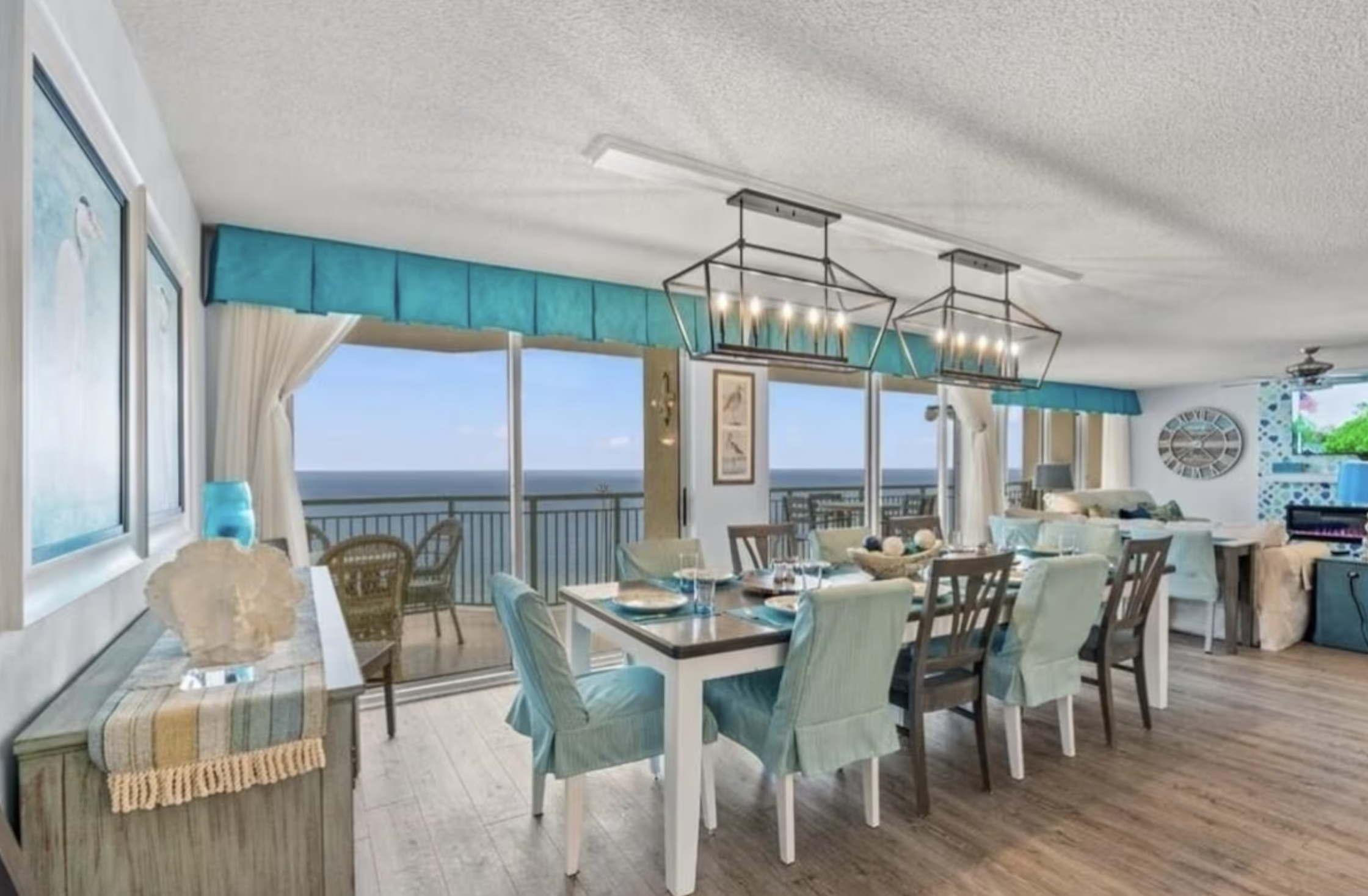 The large dining table in the open-concept living space seats a large family, and features a wall of sliding glass doors for incredible ocean views.