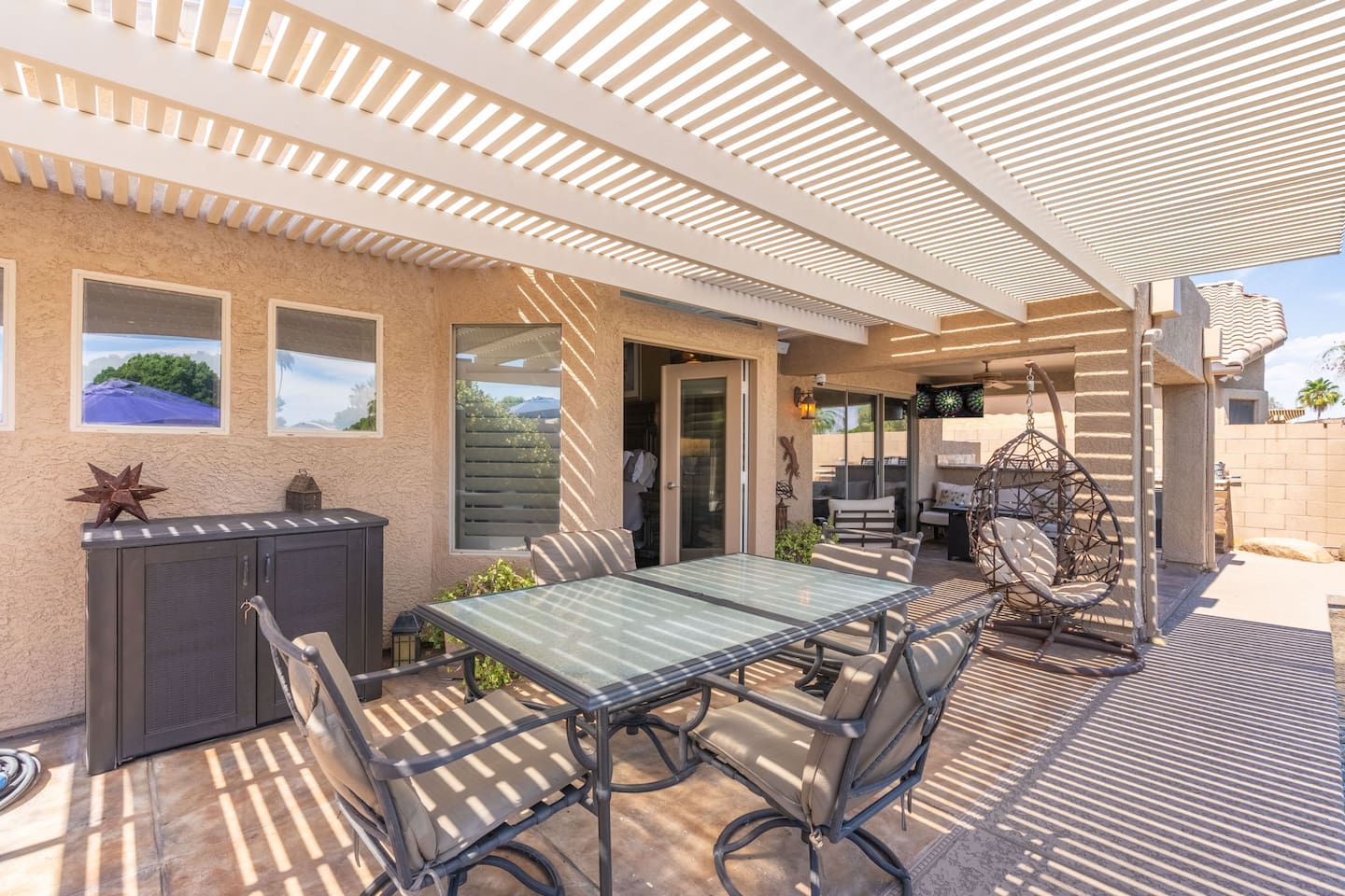 The pergola dining area offers a generous al fresco table for the whole group, with the hanging egg chair nearby for anyone who wants to linger a little longer after the meal.