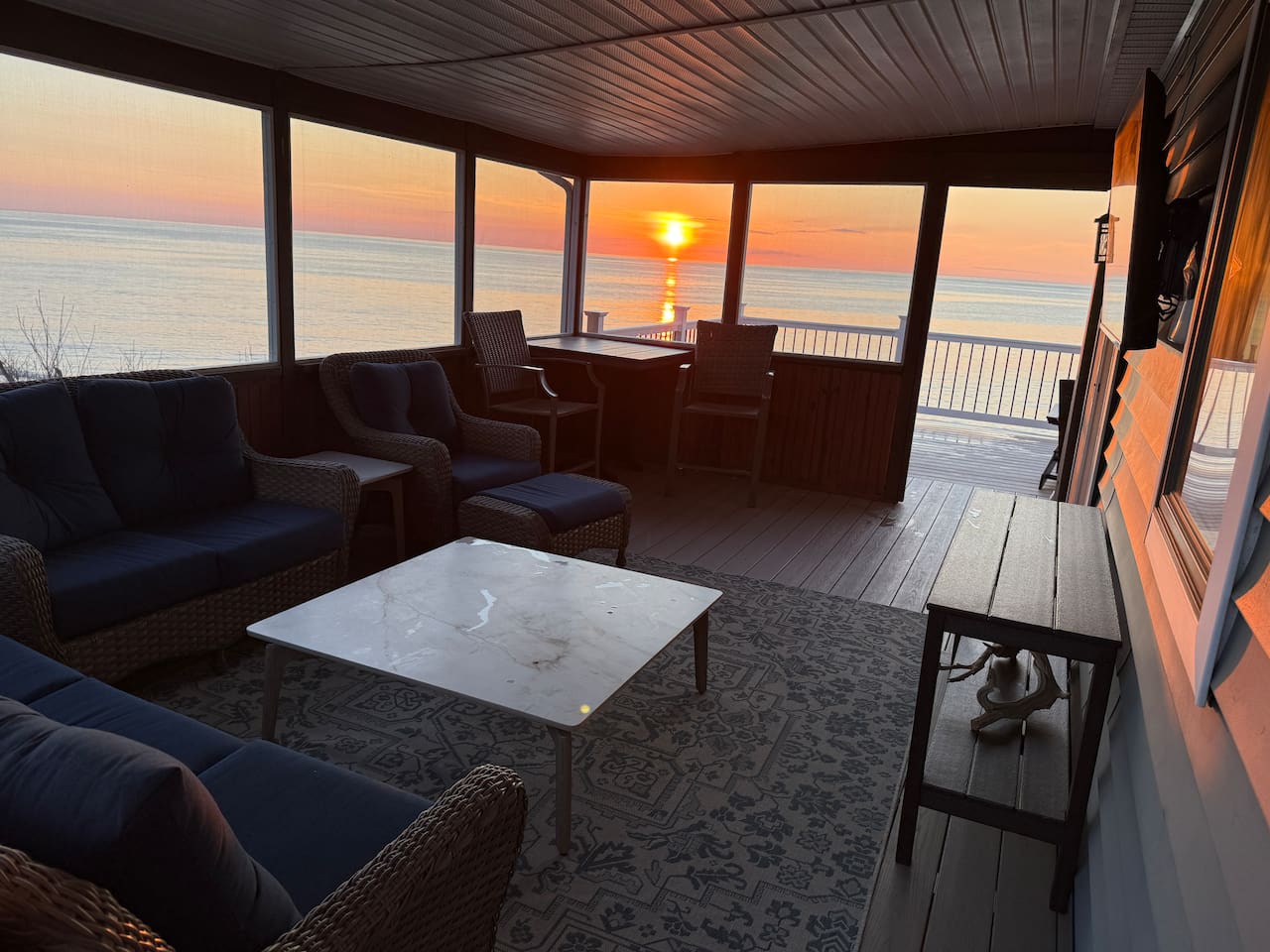 Enjoy breathtaking sunset views from the comfort of this elegant, screened-in porch. This serene luxury space features plush wicker seating, perfect for relaxing as you watch the sun set.