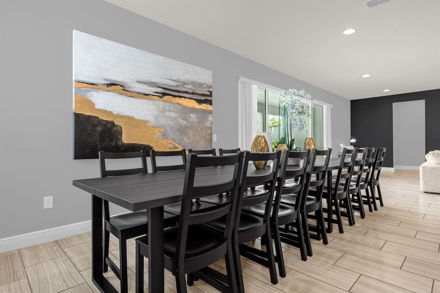 The dining area features a long, elegant table that seats 16, perfect for large gatherings. Above the table, a beautiful painting hangs on the wall, adding a touch of sophistication and charm to the space, creating a warm and inviting atmosphere.