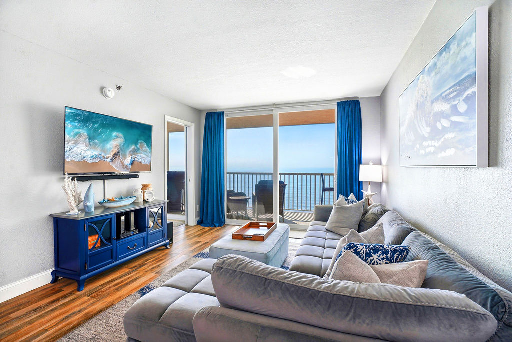 Relax in this bright coastal-inspired living space with ocean views, plush seating, and seamless balcony access for the ultimate beachside getaway.