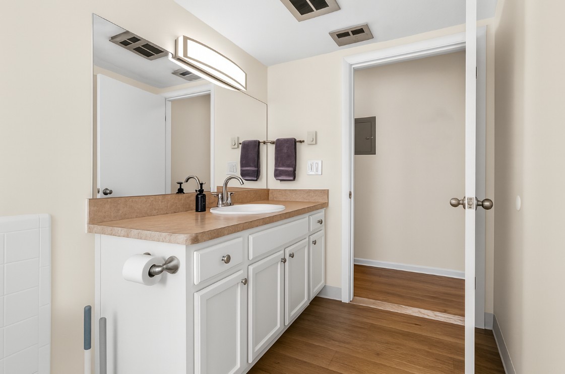 Clean and modern bathroom with full-size tub, granite vanity, and bright lighting.