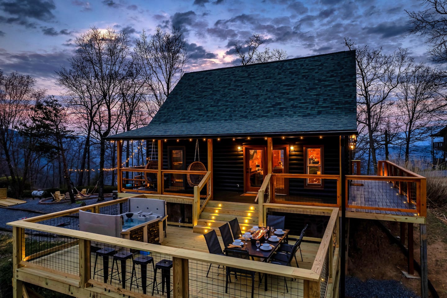 This is the rear view of the cabin showing the outdoor dining and hot tub area on the deck.