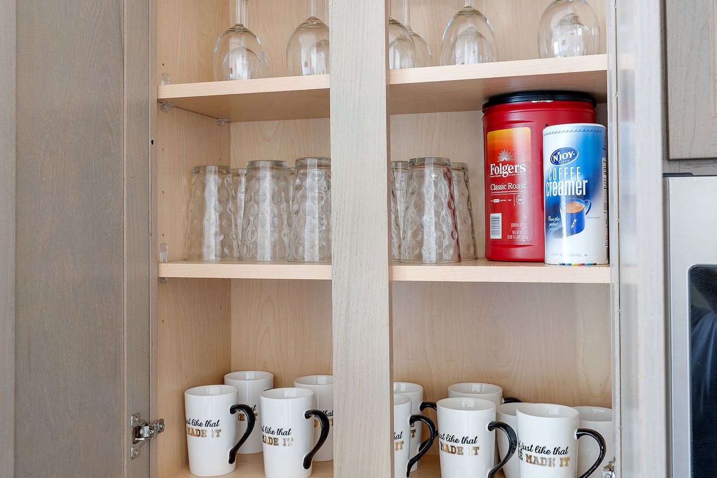 Step into a well-organized kitchen cabinet featuring an array of glassware and coffee mugs. 