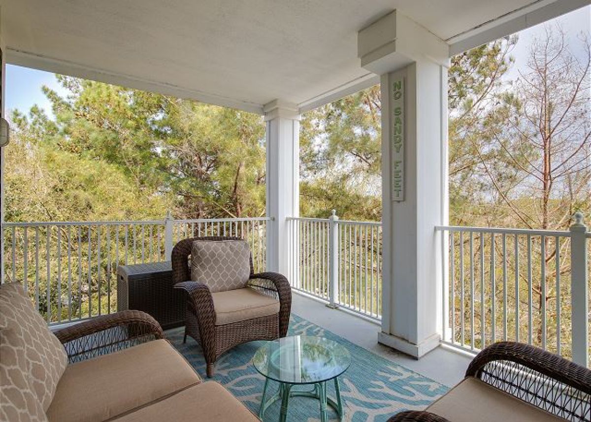 Covered balcony with wicker seating for four and resort garden views from the fourth floor