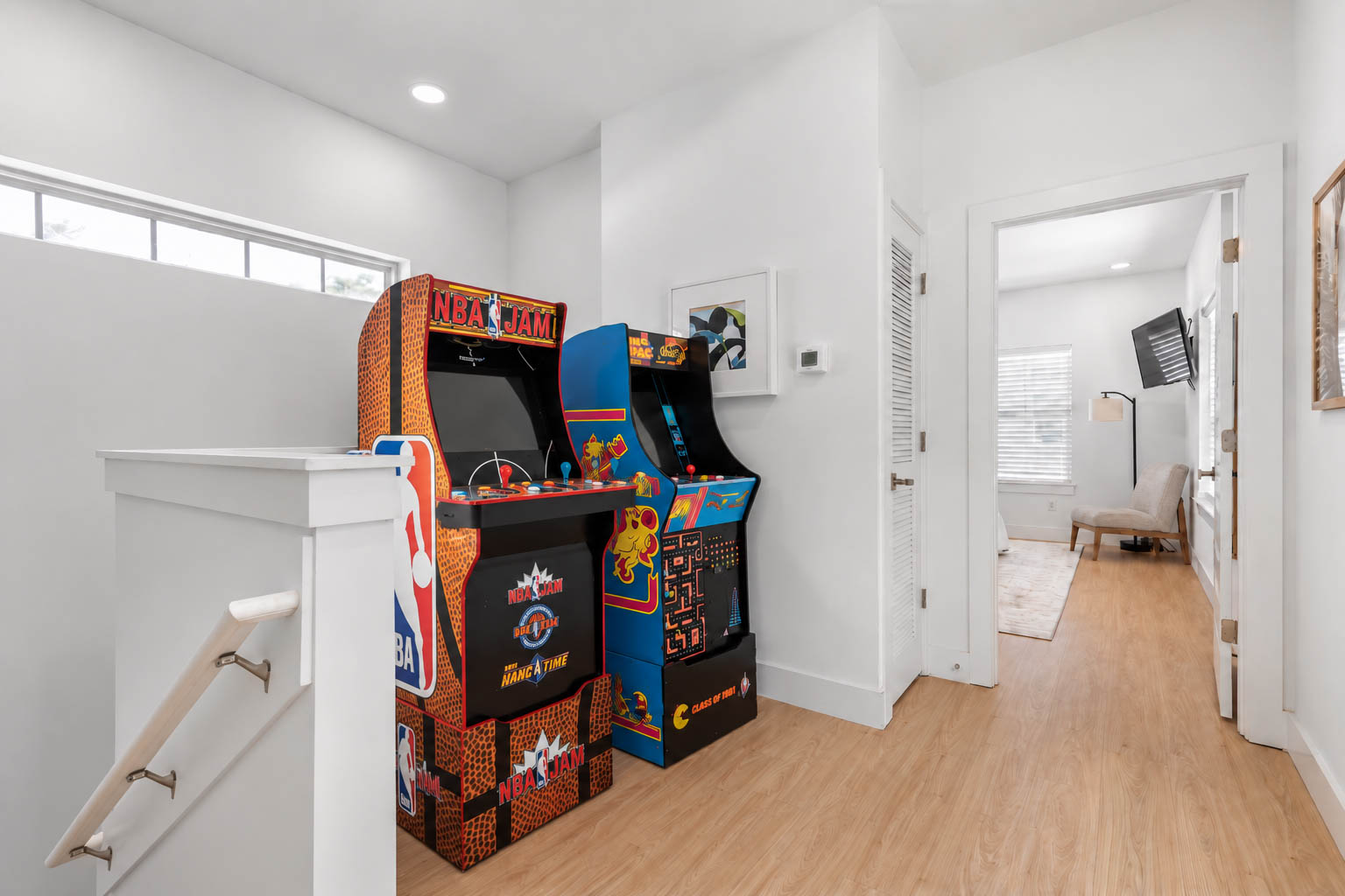 Here is where the arcade lives - top of the stairs, impossible to walk straight past. NBA Jam and Ms. Pac-Man in full-size cabinets, and the sound of them is how you know the kids are still awake up there.
