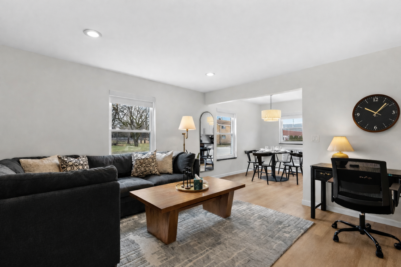 Relax in this bright, open living space with plush sectional seating, stylish décor, and a dedicated workspace flowing into a cozy dining area.
