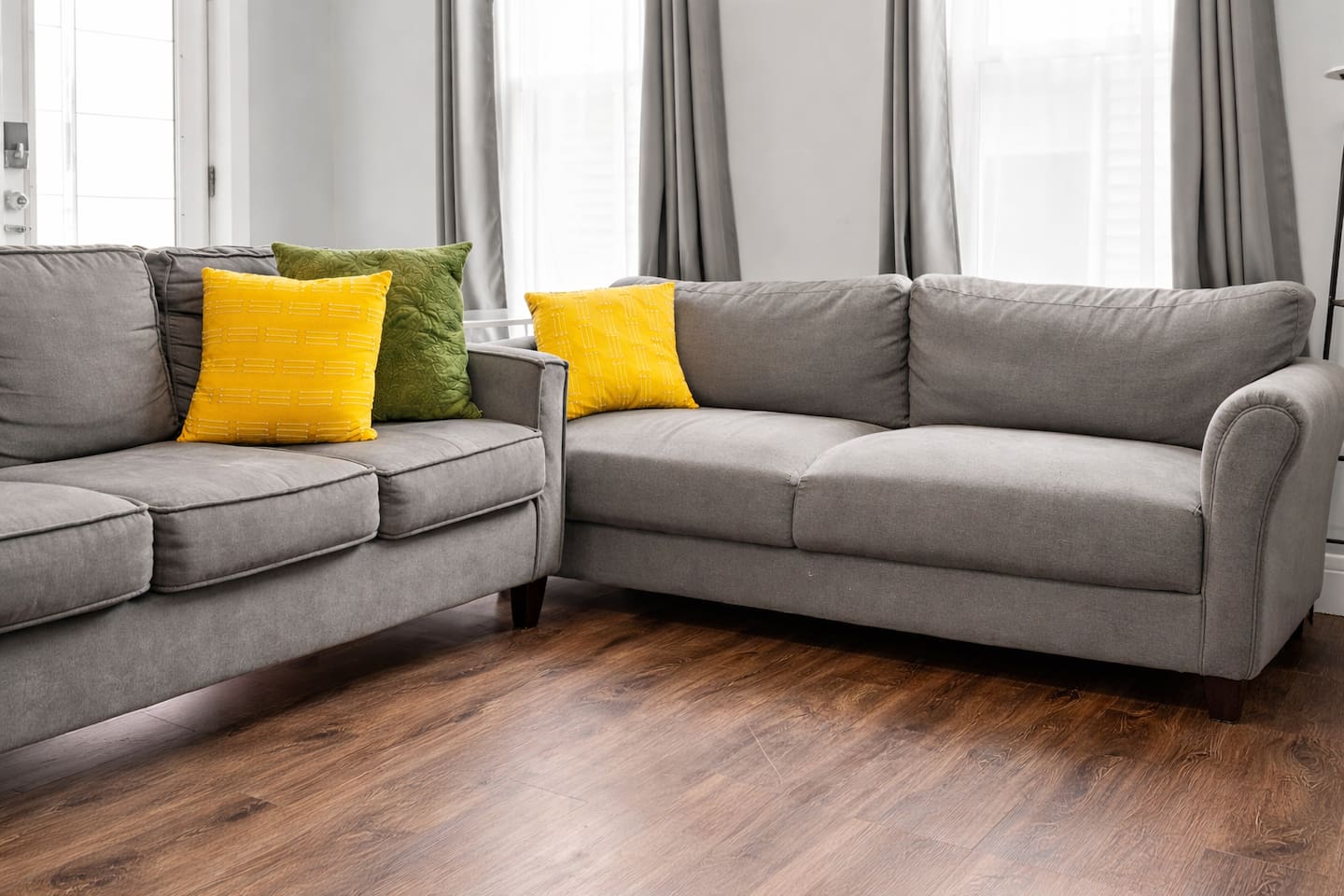 Sunlit cozy living room with plush sofas and bright accent pillows.