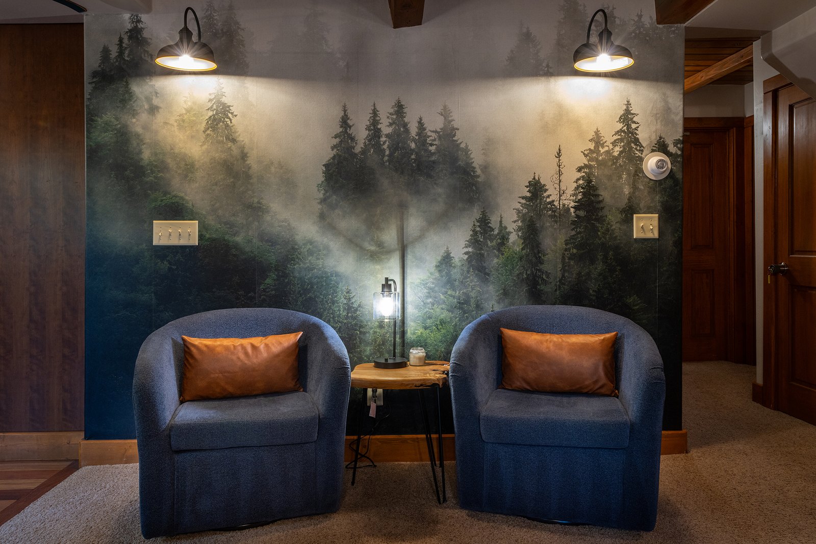 Pull up a chair beneath the forest mural — the quiet corner of the great room where someone always lands with a book and a coffee.