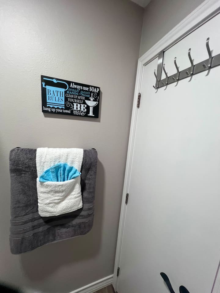 Bathroom detail with wall hooks and a reminder sign for guest use.
