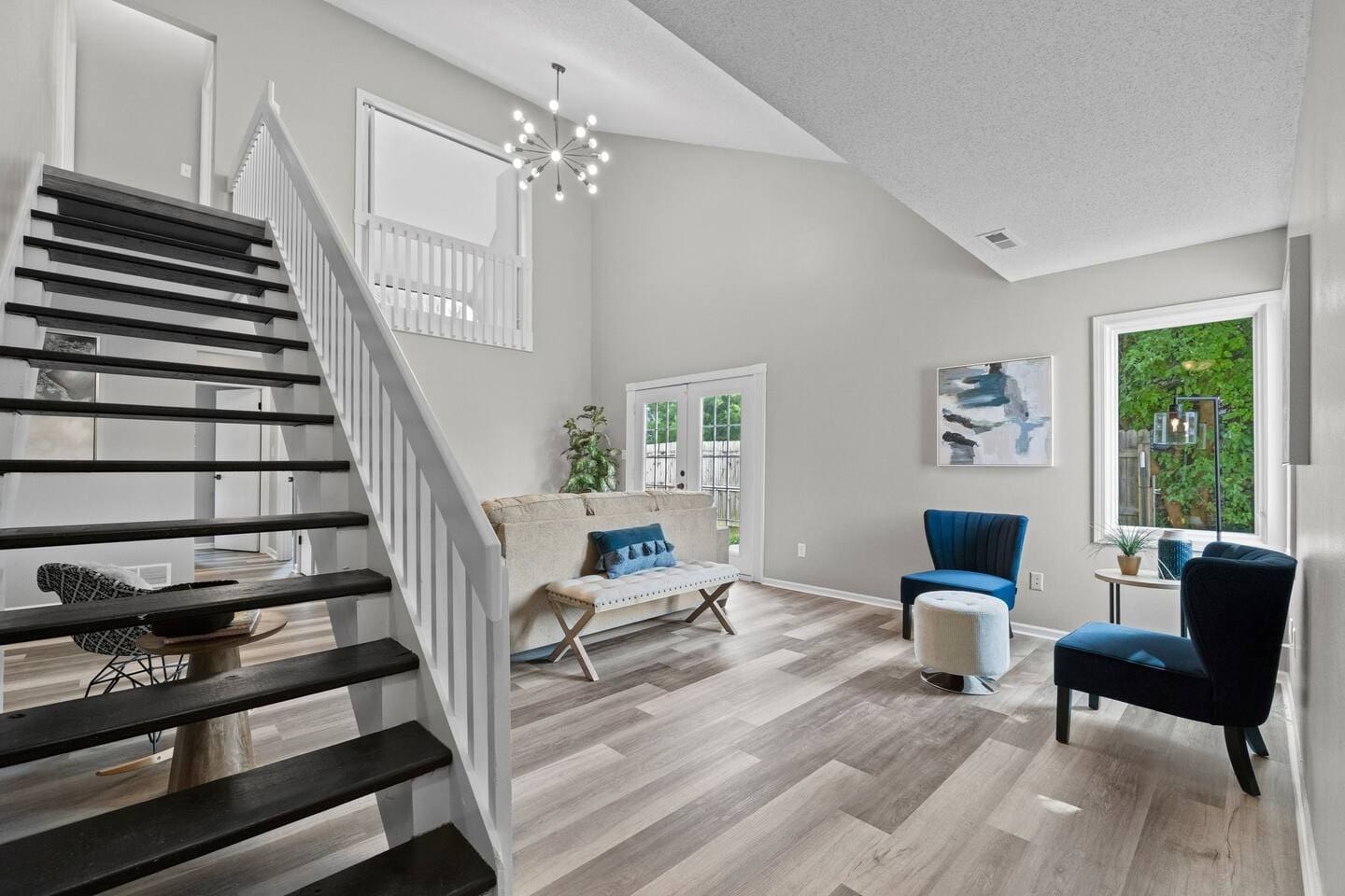 Bright and open living area featuring a beautiful single couch, with easy access to the stairs for added convenience.