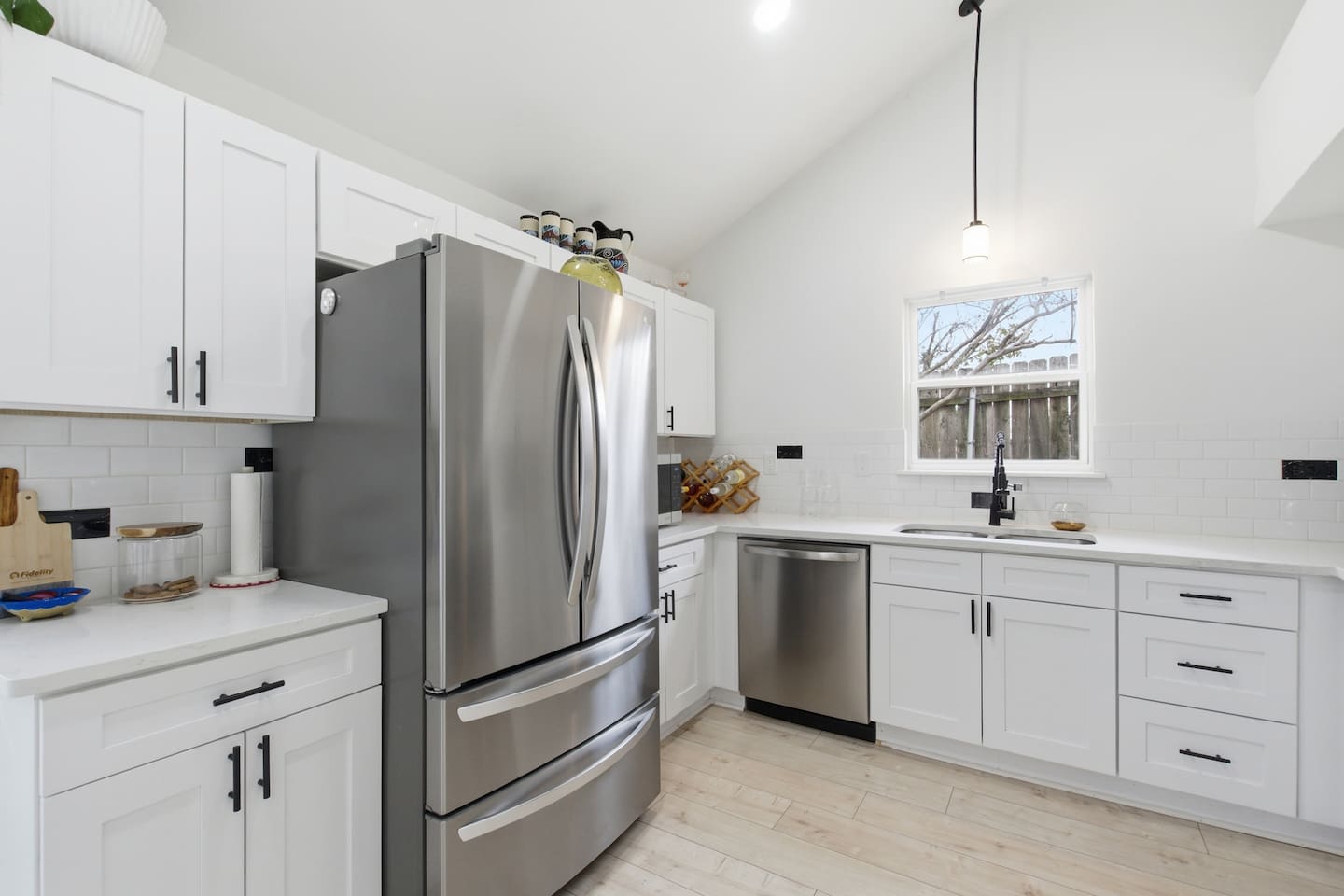 Bright full kitchen with stainless steel refrigerator, dishwasher, microwave, oven, and spacious countertops for easy cooking and meal prep.