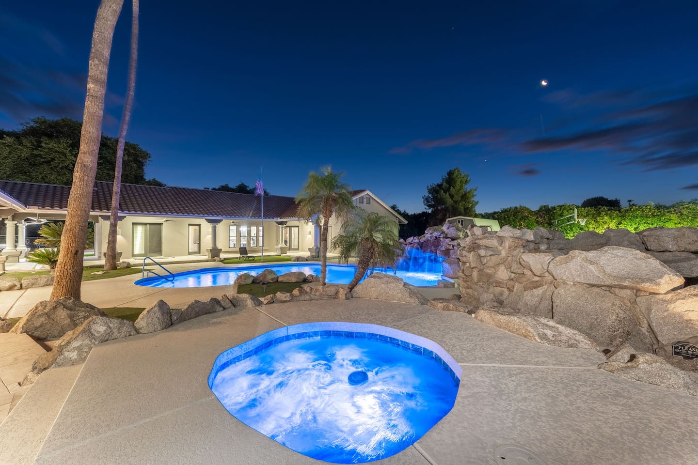 Enjoy a peaceful soak with views of the waterfall pool and glowing tropical landscaping.