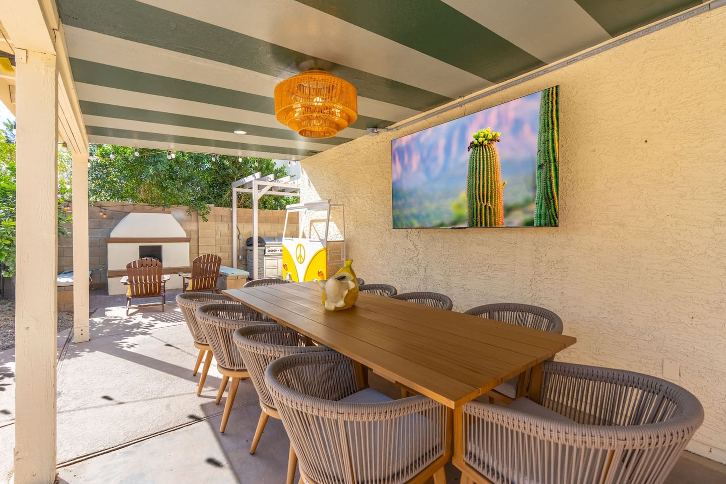 Spacious covered patio with striped ceiling, dining table, desert art, and direct pool access—seamless indoor-outdoor entertaining.