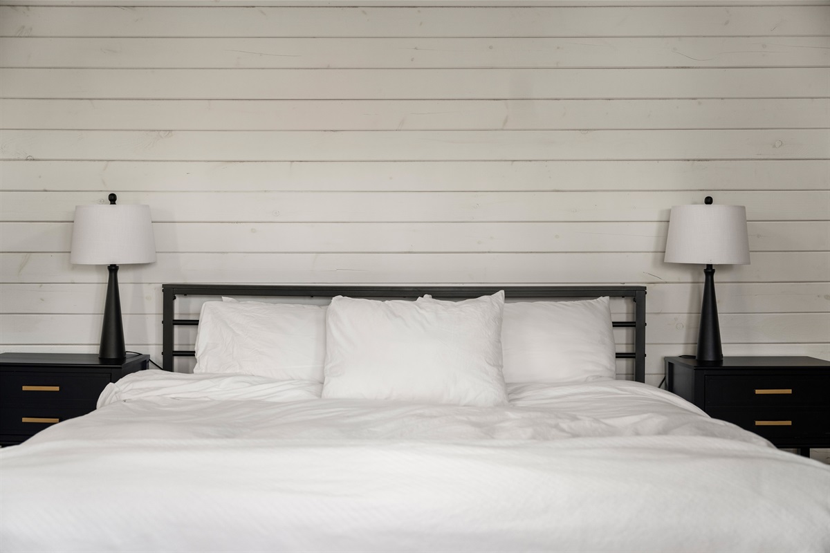 Bedroom 1: Sunlit space with sleek decor, inviting bedding, and modern lamps for a restful stay!