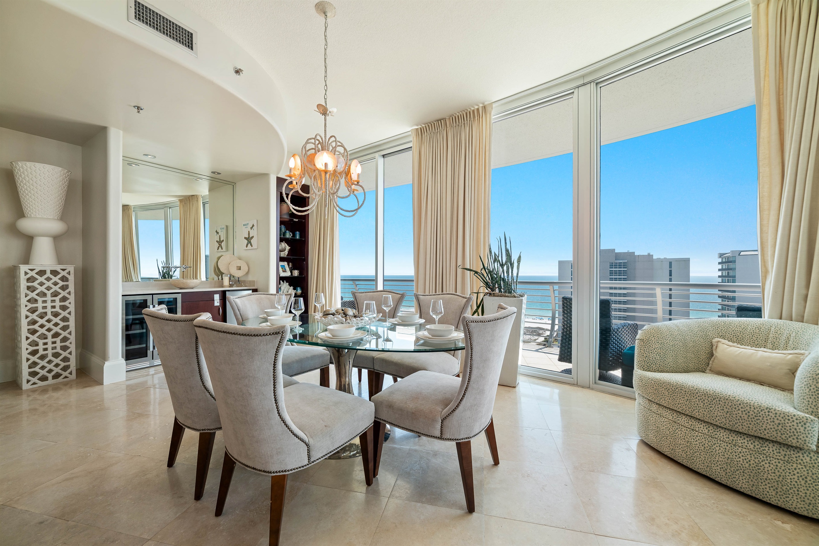 Sophisticated dining with panoramic coastal views. This exquisite 6-seater dining area is the centerpiece for formal entertaining, featuring premium stone flooring, custom cabinetry, and a captivating waterfront backdrop