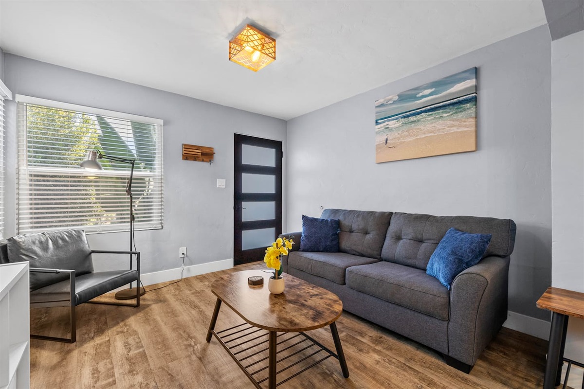 Unwind in a stunning living room adorned with a lovely painting, comfortable sofa, and chic coffee table. Enjoy movie nights with the TV and the cozy glow from a stylish chair, perfect for your getaway!