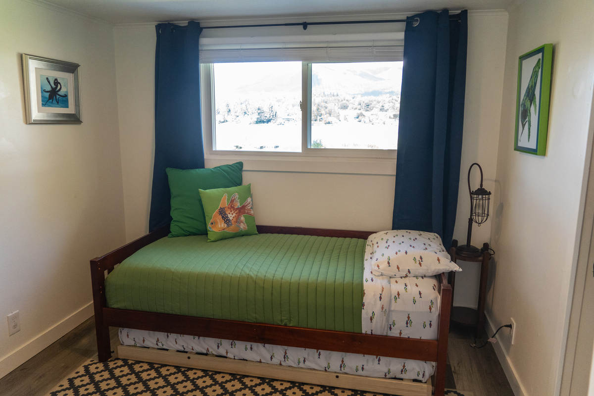 A whimsical space for kids with twin and trundle beds, where ocean creatures and moonlit adventures inspire imagination, all with a peaceful lake view just beyond the window.