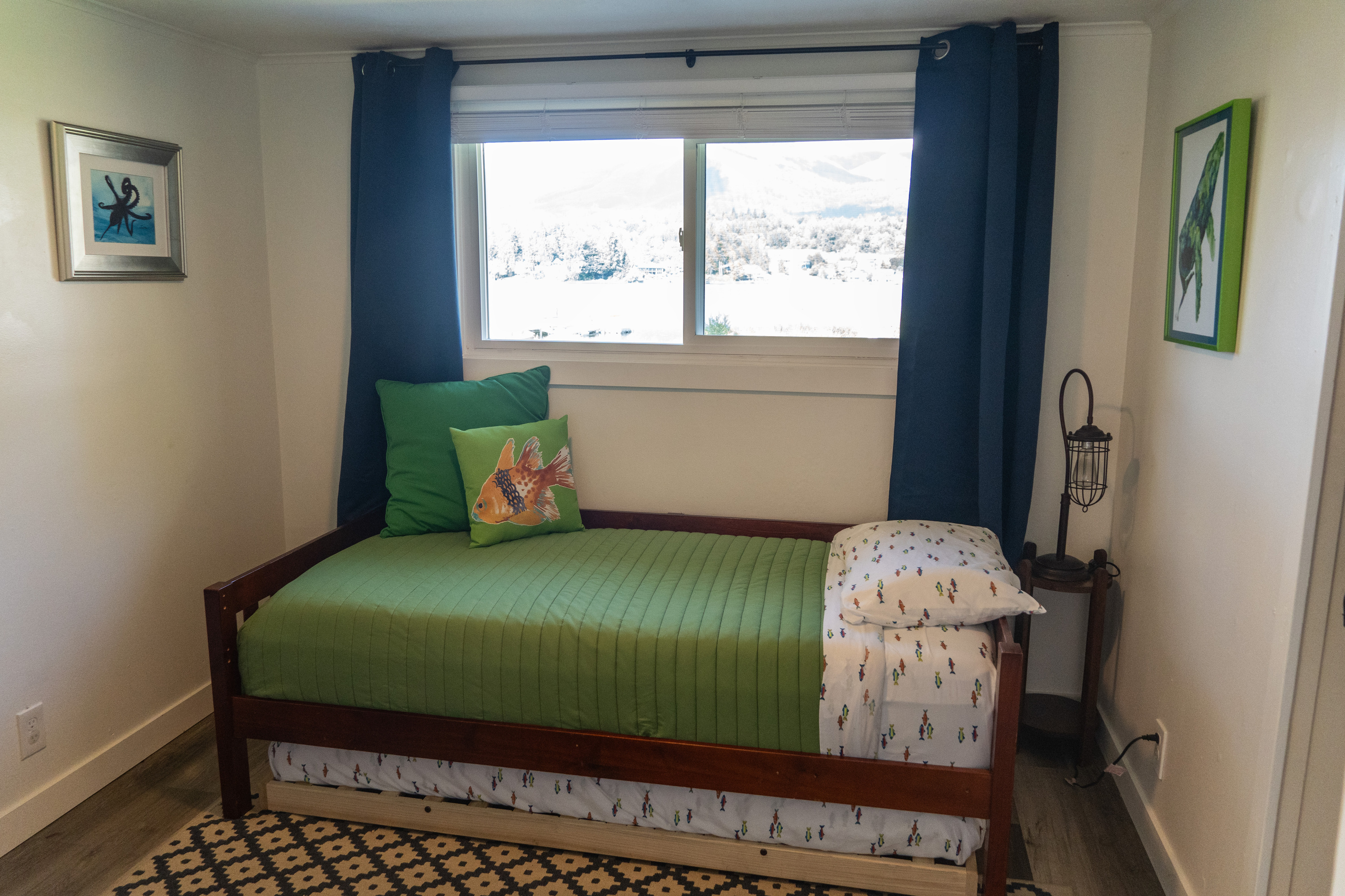 A whimsical space for kids with twin and trundle beds, where ocean creatures and moonlit adventures inspire imagination, all with a peaceful lake view just beyond the window.