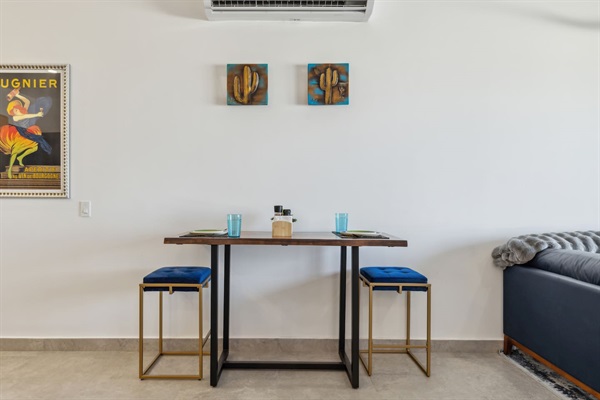 Sleek 2-stool table setting, ideal for two. Above, bold gold and turquoise metal cactus art adds a modern, stylish vibe to this Airbnb space.