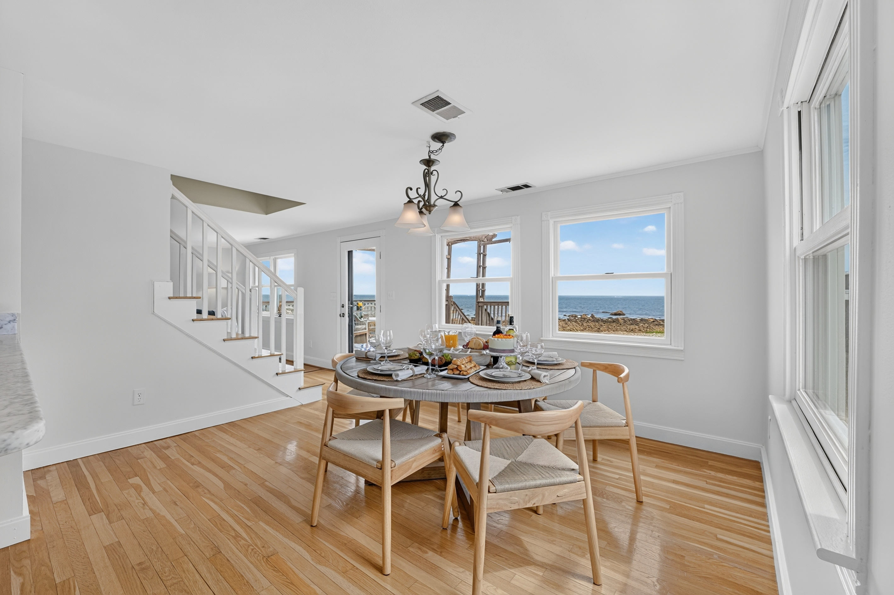 Enjoy meals together in a bright dining space surrounded by windows and coastal scenery.