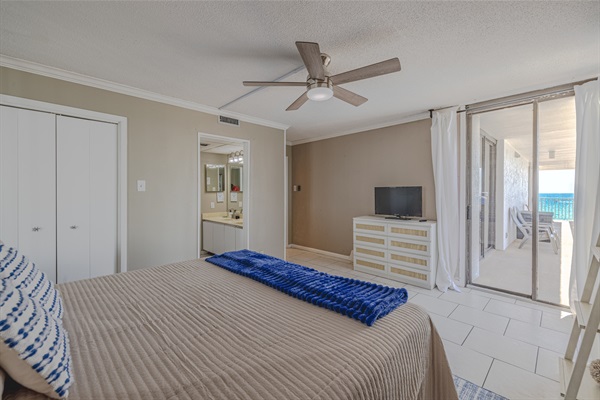 Master bedroom #1 with ensuite bath, ceiling fan, smart TV, and balcony access