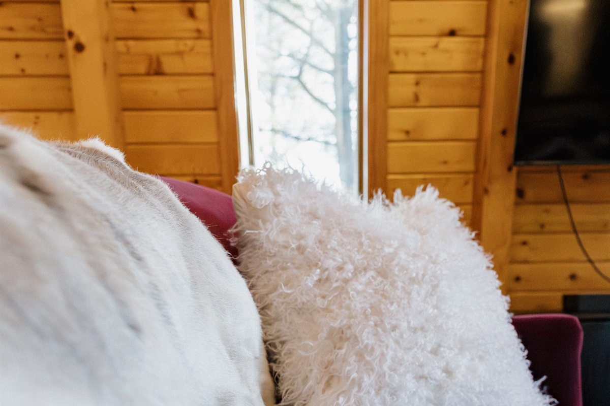 Sink into plush velvet seating with soft faux fur accents at Poppywood Pines. This cozy Show Low cabin blends luxury comfort with rustic charm, creating the perfect space to relax after exploring White Mountains trails, lakes, and outdoor activities.