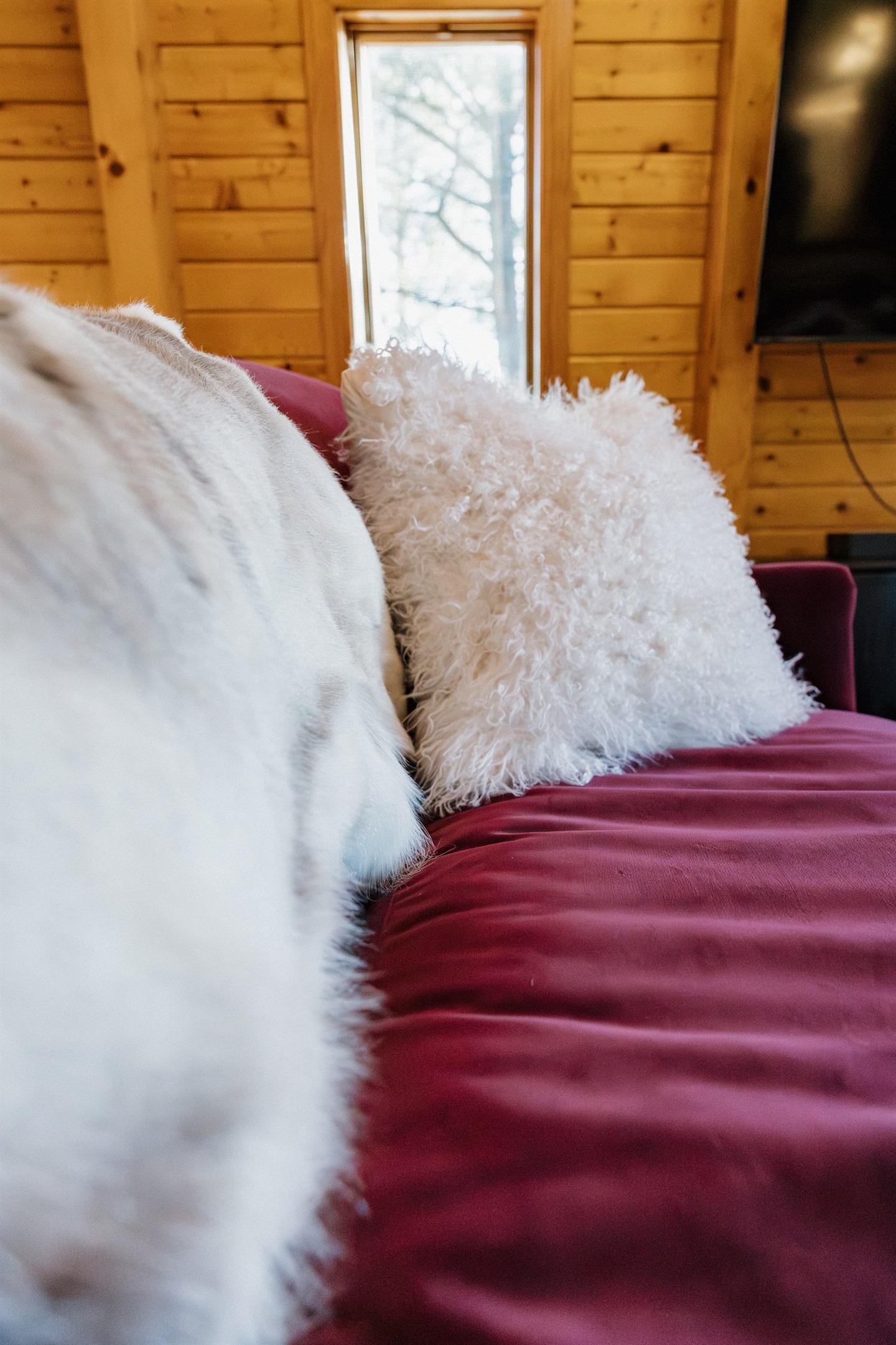 Sink into plush velvet seating with soft faux fur accents at Poppywood Pines. This cozy Show Low cabin blends luxury comfort with rustic charm, creating the perfect space to relax after exploring White Mountains trails, lakes, and outdoor activities.