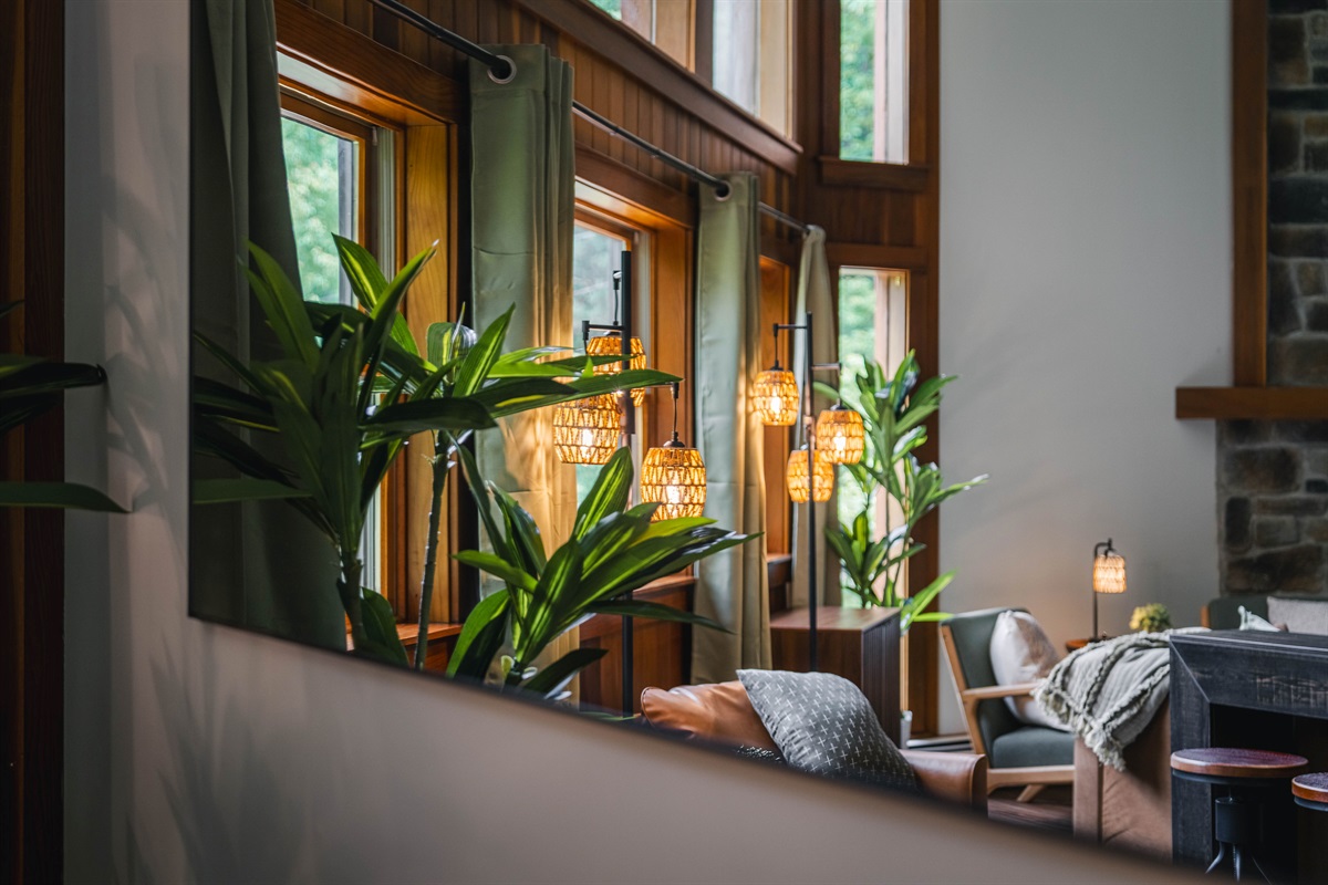 A warm, stylish living space bathed in natural light and surrounded by greenery