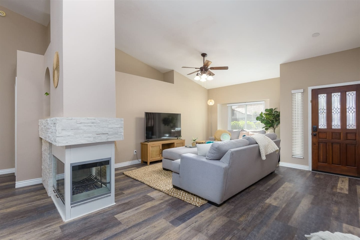 Living room with vaulted ceiling, large Smart TV, comfortable sectional seating, and room to relax or gather indoors.