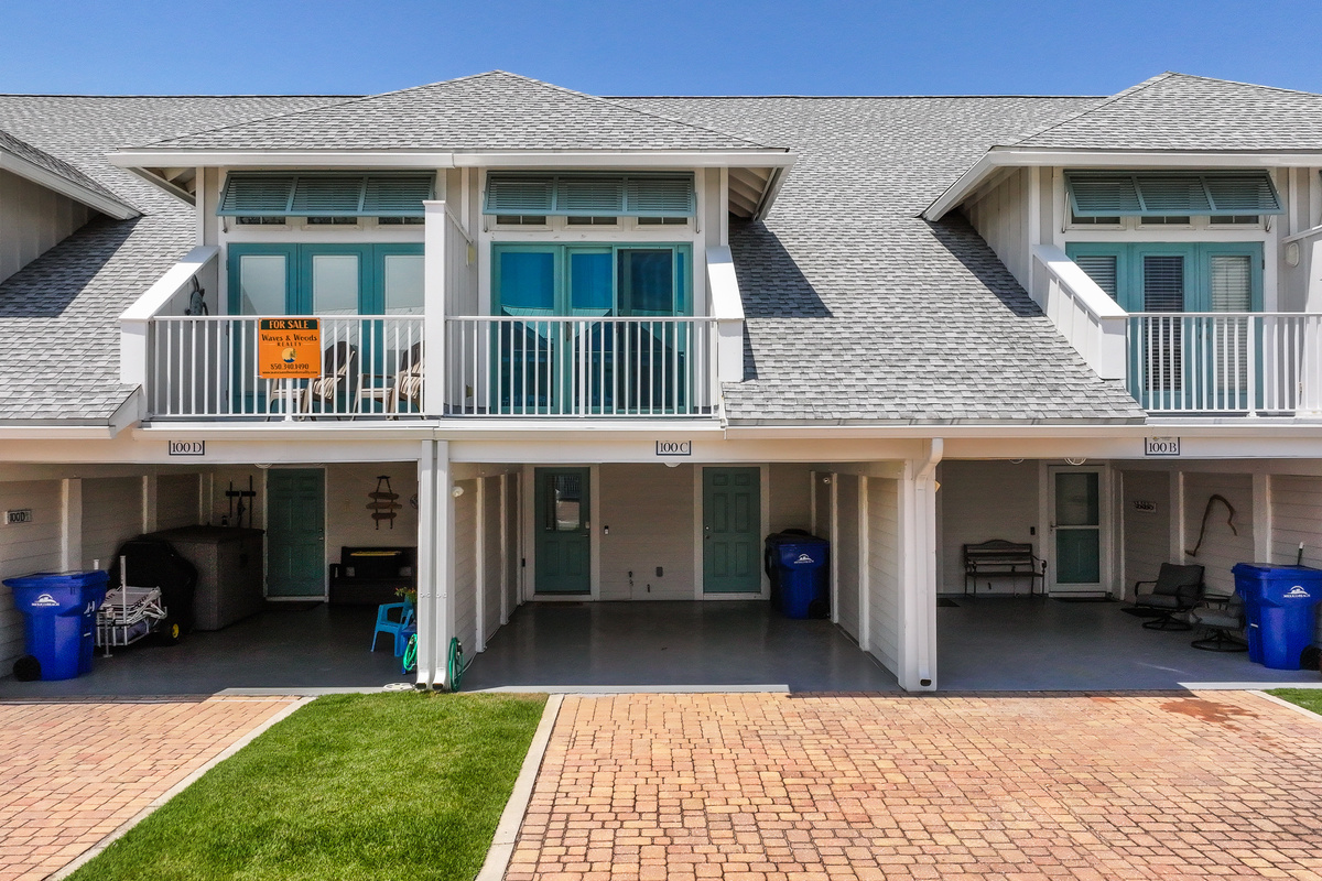 Bright coastal townhome with a private driveway, carport, and a welcoming entrance, perfect for a relaxing beach getaway.