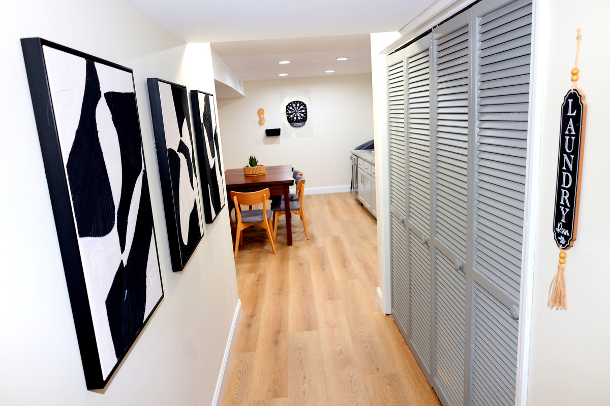 Lower-level hallway with laundry room access, game area, and stylish décor