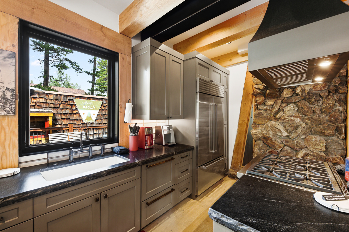 Chef's kitchen with view of outdoor living space, center cooking island, gorgeous custom cabinetry and a mix of design textures. 