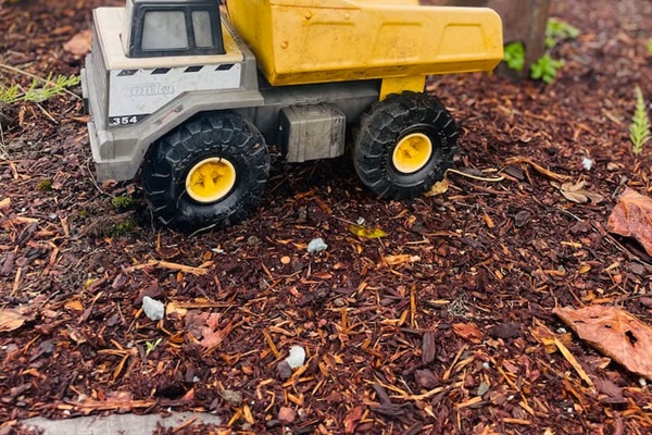 An old-style Tonka truck sits ready for imaginative excavating in the yard, inviting kids to dig, play, and explore in the open outdoor space.
