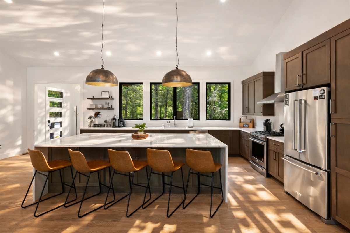 The spacious kitchen island includes plenty of seating, perfect for gathering while enjoying the natural light from the surrounding windows.
