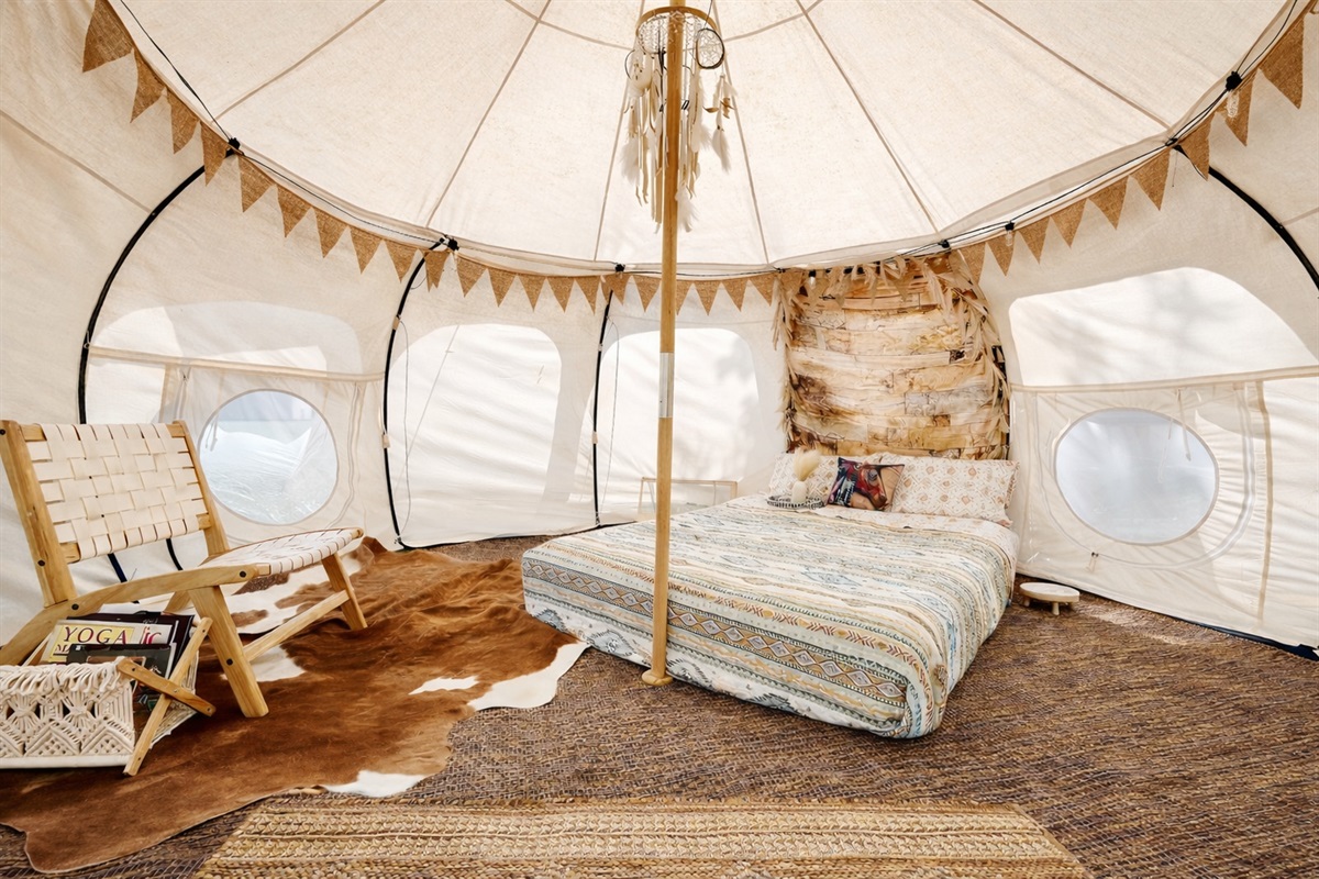Enjoy this 13ft Lotus Belle tent, complete with a comfy queen-size bed, clean linens, and a sitting area with books