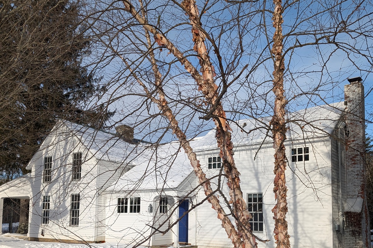 Classic Vermont farmhouse set against a peaceful winter landscape — a timeless retreat in every season.