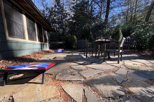 Enclosed Patio: Relax on a private stone patio surrounded by trees, perfect for outdoor dining and games