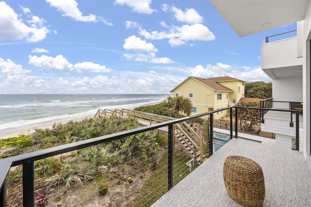 Enjoy breathtaking views from the balcony, where the ocean meets soft white sand, and a picturesque bridge stretches towards the sea, offering the perfect spot to relax and take in the stunning coastal scenery.