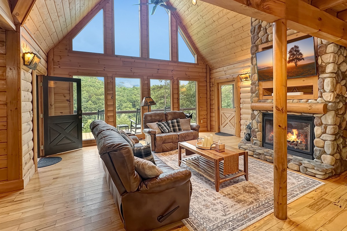 Living Room: Sunlit space with stunning views, a stone fireplace, and inviting leather sofas!
