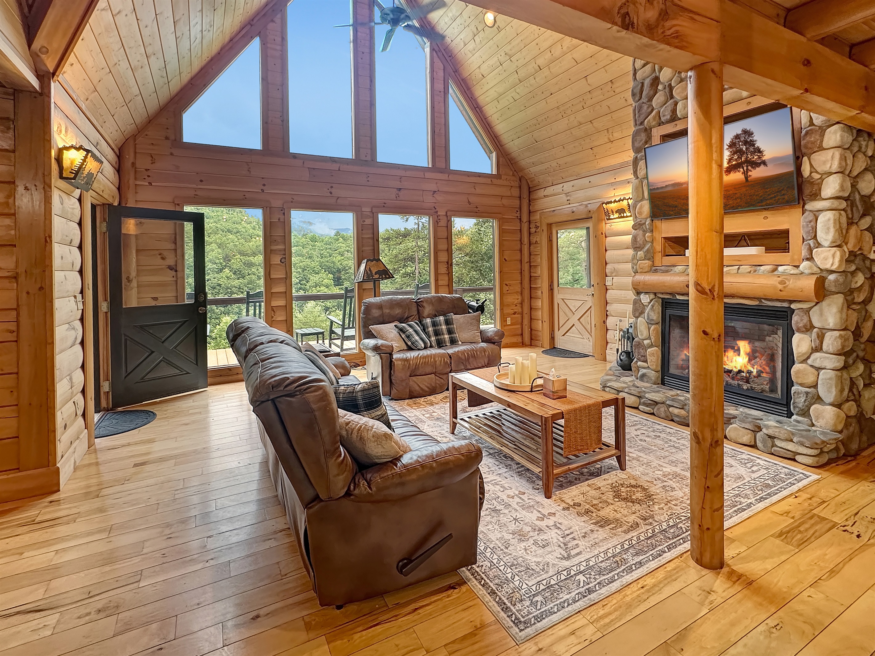 Living Room: Sunlit space with stunning views, a stone fireplace, and inviting leather sofas!
