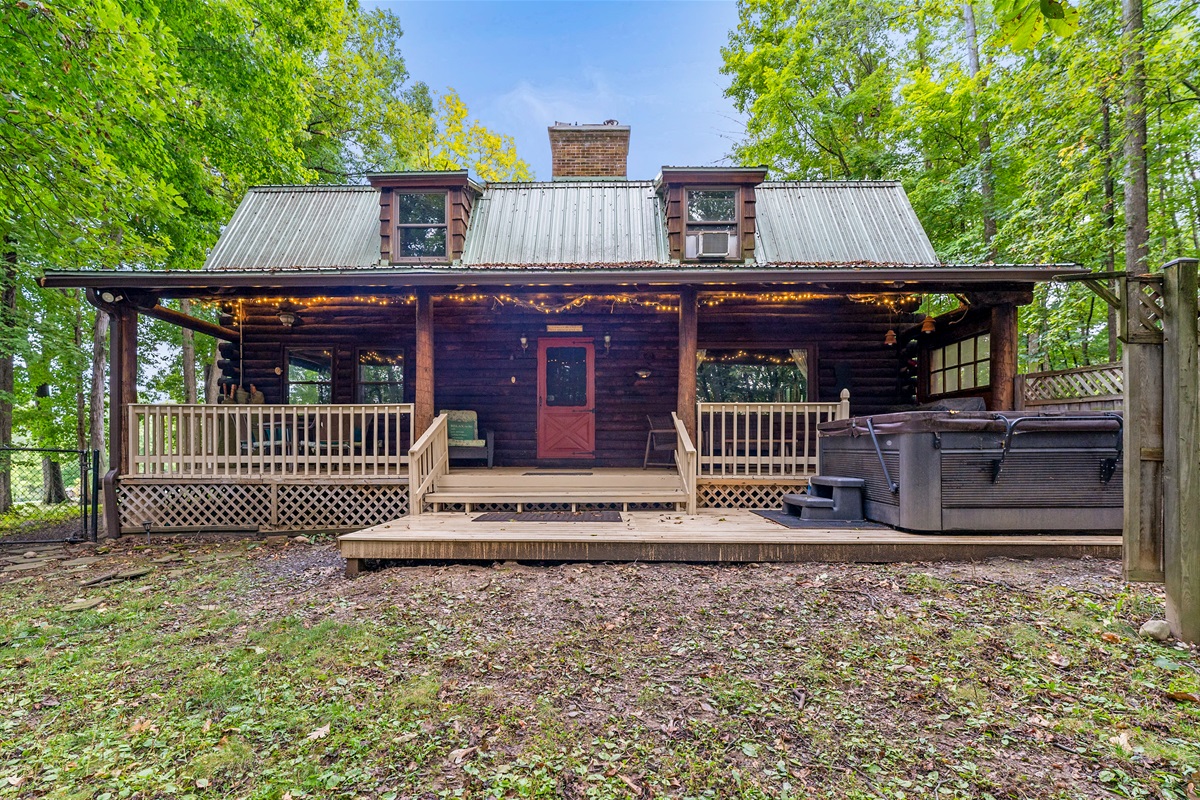 Charming log cabin retreat featuring a spacious side deck, bubbling hot tub, and string-lit porch—your perfect Finger Lakes getaway.
