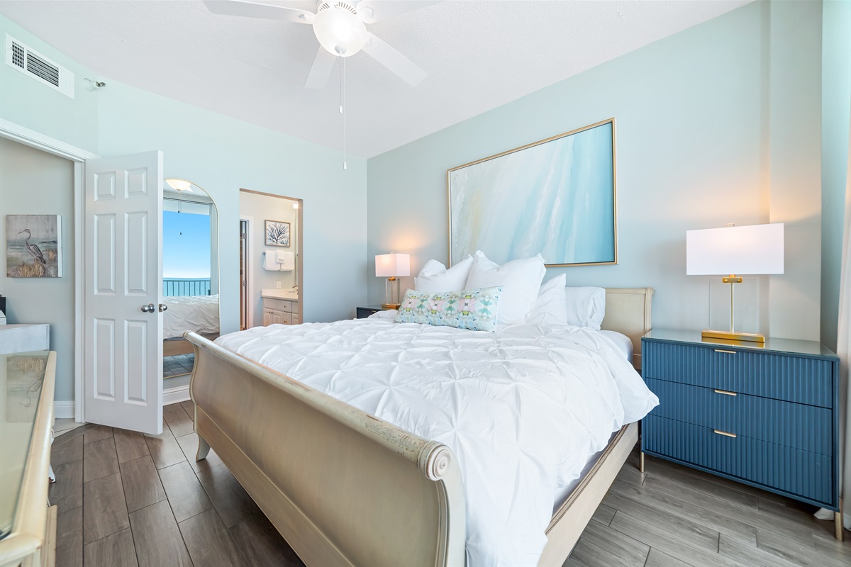 This well-appointed Primary bedroom features a king -size bed with a decorative headboard, crisp white bedding, matching nightstands with lamps, and tile flooring for easy maintenance.