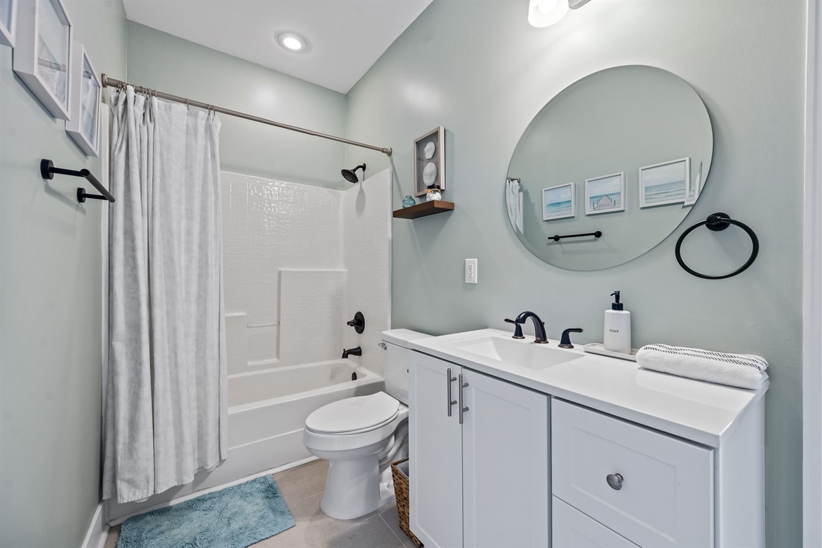 Bathroom 1 features shower/tub combo, spacious vanity, and coastal accents