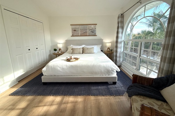 King size bed and an oversized window with lush palm-lined views of the property
