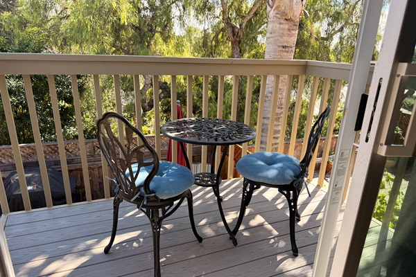 Sitting area on primary bedroom balcony overlooking backyard and mountain view