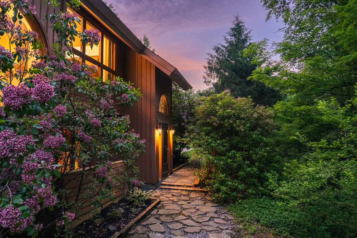 Arrive in style—this charming stone path leads you through blooming gardens to the cabin entrance.