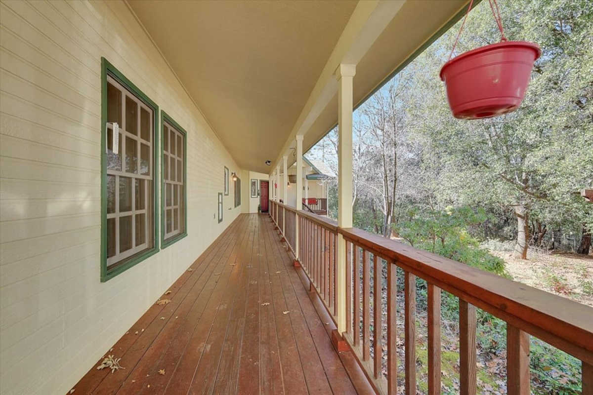 Covered porch with wood decking, wooded views, and plenty of space to walk or sit outside.
